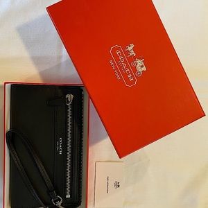 Coach black leather wristlet with silver-tone hardware, 7 1/2” (L) x 4 3/4” (H).